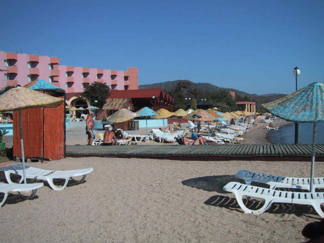 Blick vom Strand zur Promenade und dahinter das Restaurant und Hotel