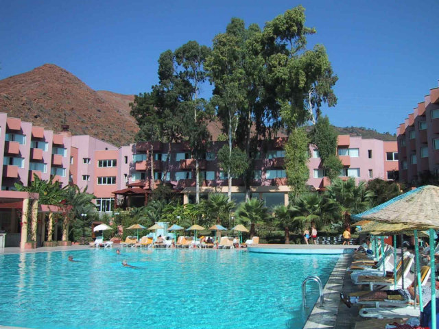 Hotel hinter schattigen Bäumen und davor der große Pool